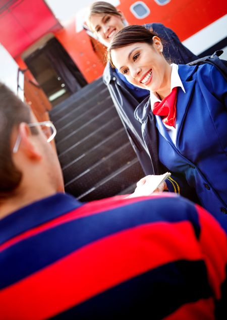 Friendly air hostesses welcoming passenger into the airplane