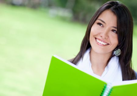 Beautiful woman portrait studying outdoors with a notebook