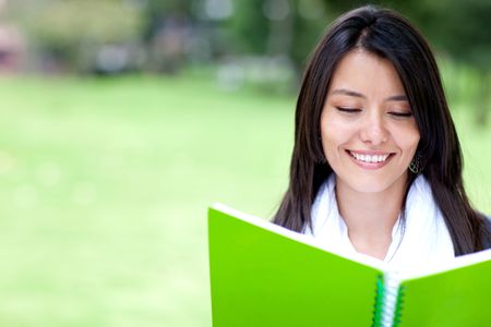 Portrait of a beautiful woman reading on her notebook - outdoors