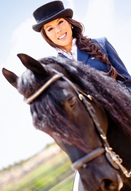 Beautiful horsewoman riding a horse outdoors and smiling