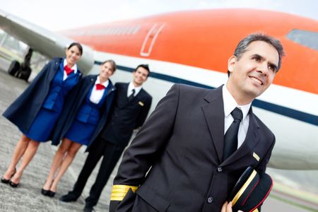 Captain pilot with cabin crew and an airplane at the background