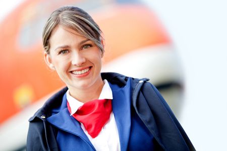 Beautiful air stewardess with a airplane at the background and smiling