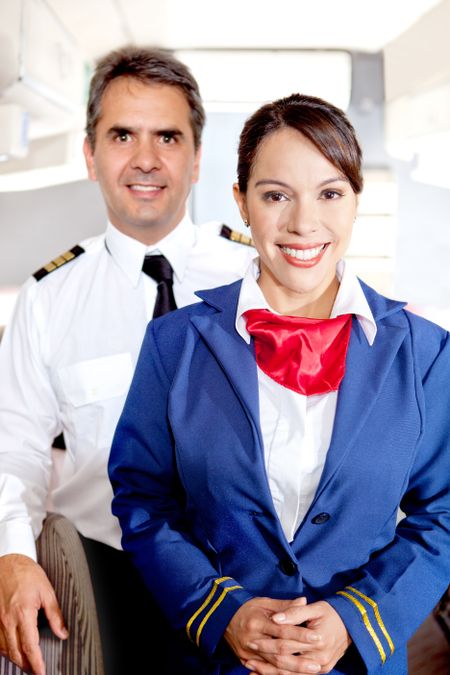 Pilot and air hostess in an airplane cabin smiling