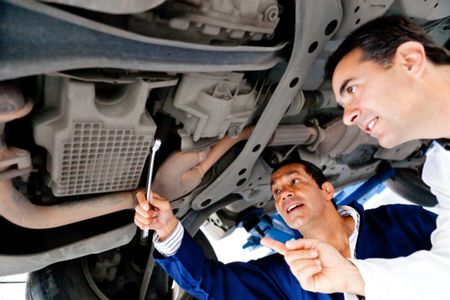 Mechanics fixing a car underneath at the garage