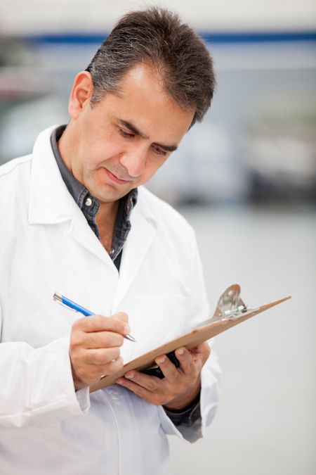 Man working as mechanic in a car garage and taking notes