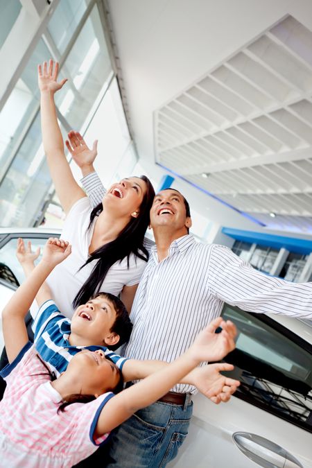 Family celebrating buying a new car with arms up