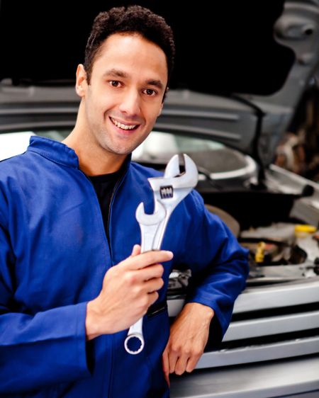 Mechanic working at a repair shop and holding tool