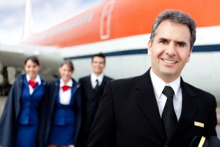 Captain pilot with cabin crew and an airplane at the background