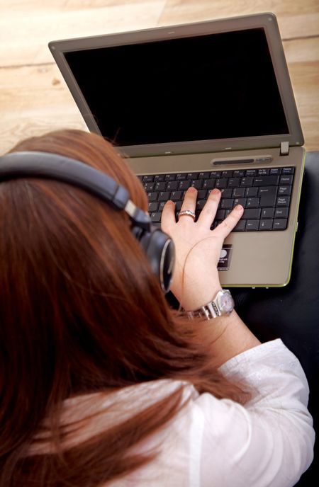girl browsing the internet on a laptop while listening to music using headphones