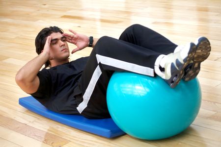 man at the gym doing abs exercises with a pilates ball
