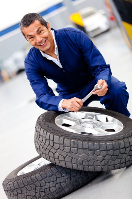 Male mechanic fixing car tire at the garage