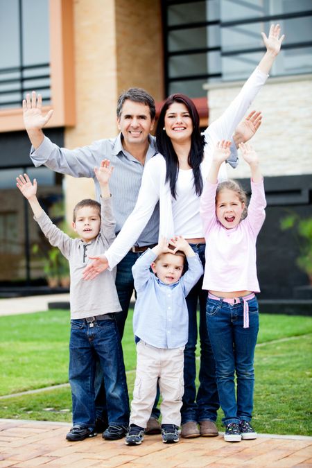 Happy family with arms up in front of a house