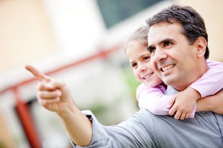 Father and girl pointing away and smiling - outdoors