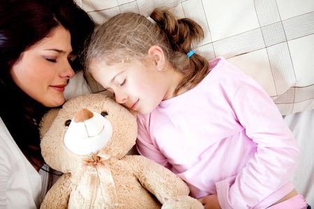 Girls bedtime sleeping with her mother and a teddy bear