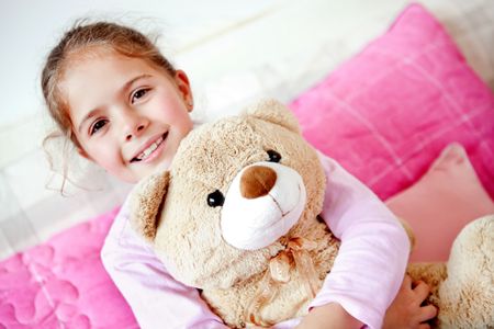 Little girl in bed hugging her teddy ber