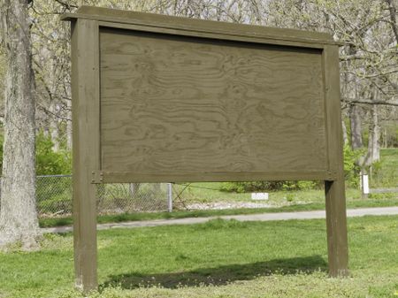 Your message here: Blank wooden signboard in state park on a spring afternoon